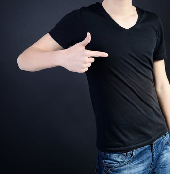 Young man in blank black t-shirt over dark background, teen boy