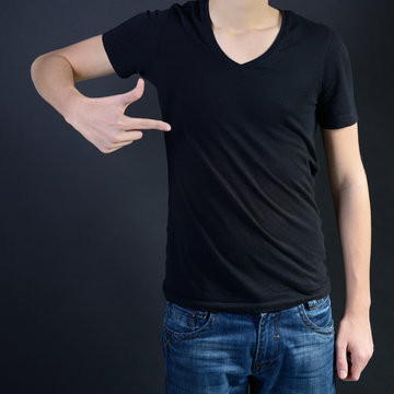 Young man in blank black t-shirt over dark background, teen boy