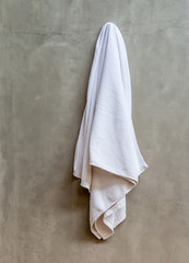 Fototapeta premium Hanging white towel draped on exposed concrete wall in the bathr