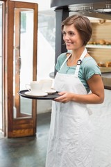 Pretty barista smiling and holding tray