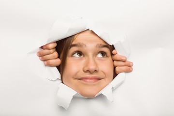 Cute little girl peeking through paper