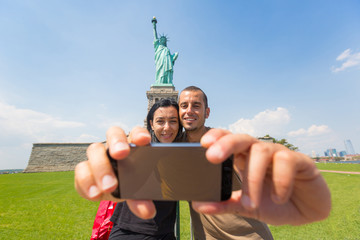 Fototapeta premium Couple Taking a Selfie with Statue of Liberty on Background