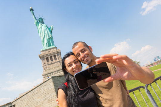 Couple Taking a Selfie with Statue of Liberty on Background