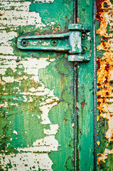 Hinge on rusty metal door with cracked paint