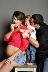 Happy family with pregnant woman on gray background