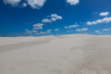 Fototapeta na wymiar White sand and clouds against a blue sky