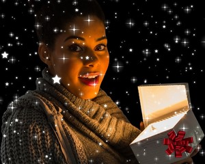 Composite image of pretty girl opening a glowing gift