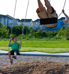 Father and son playing on the swing set at the playground