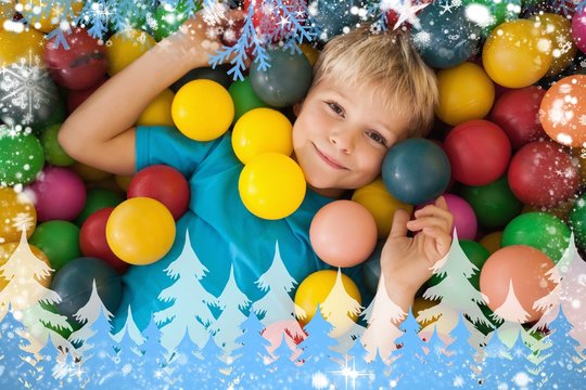 Composite image of happy boy playing in ball pool