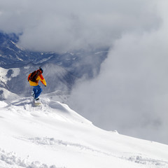 Snowboarder on off-piste slope an mountains in mist