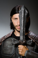 Angry knight with sword against dark background