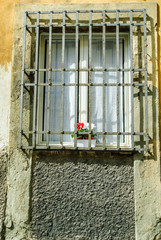 Fototapeta na wymiar Finestra con inferiate, vaso di fiori