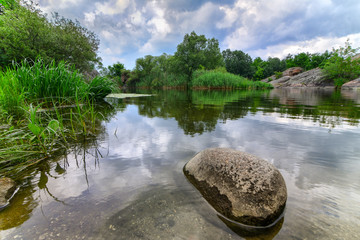 Beautiful river boulder with sky stormy clouds,  moving water - 70725888