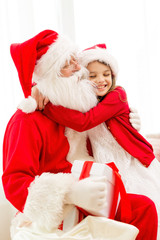 smiling girl with santa claus and gift at home