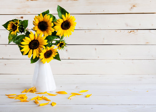 A bouquet of autumn sunflowers in a vase on a wooden table.