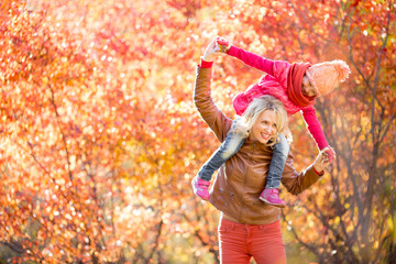 Happy mother and kid having fun together outdoor in autumn or fa
