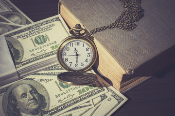 Pocket watch on bills and old book as vintage
