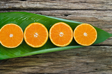 Orange fruit Slices on leaf and wooden background, nature concep