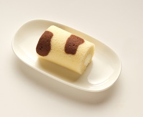 Orange chocolate roll cake in modern cream plate on cream backgr