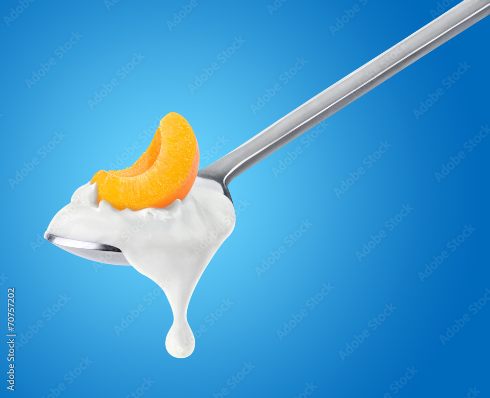 Poster isolated yogurt. spoon of yogurt with slice of peach or apricot on top over blue background, with cl