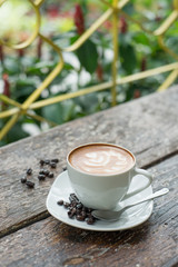 Hot latte in white cup on wood background