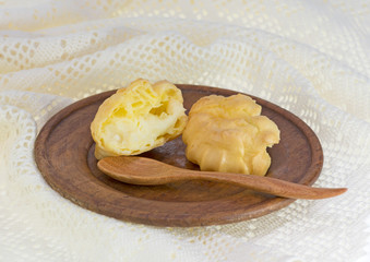 Choux buns or Eclair on wood dish and crochet  white background