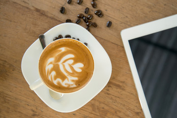 cup of coffee on table in cafe with tablet