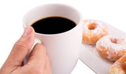 Female hand holding a mug of coffee with homemade doughnuts