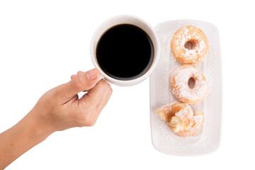 Female hand holding a mug of coffee with homemade doughnuts
