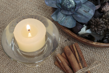 Potpourri, candle and cinnamon on burlap background