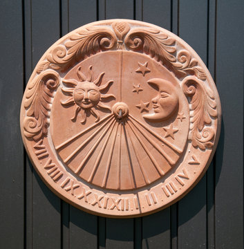 sundial made of clay hanging on a metal door