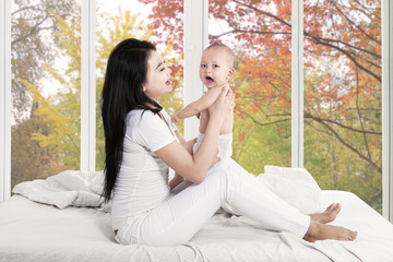 Joyful baby and mother in bedroom