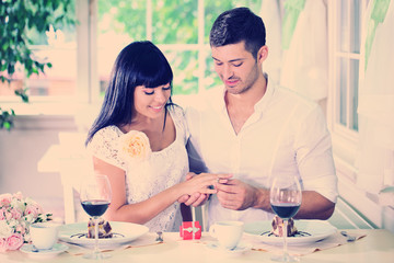 Man proposing and holding up an engagement ring his woman over