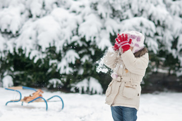little girl playing in the snow and throw snowballs
