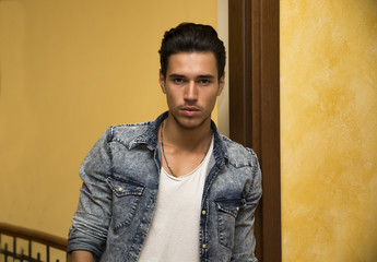 Attractive young man indoors, leaning against door jamb