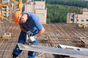 Carpenter worker cutting wood sheet with handheld circular saw