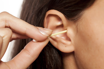 close-up of a woman cleans her ear with hygiene swab