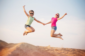 Fototapeta na wymiar two girls jumping over blue sky
