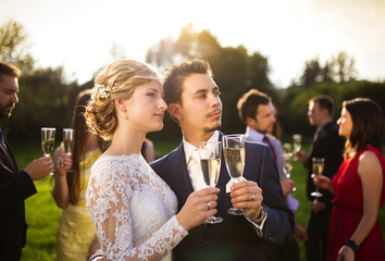 Newlyweds clinking glasses outside
