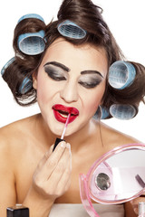 Funny woman with curlers and bad makeup applied lip gloss