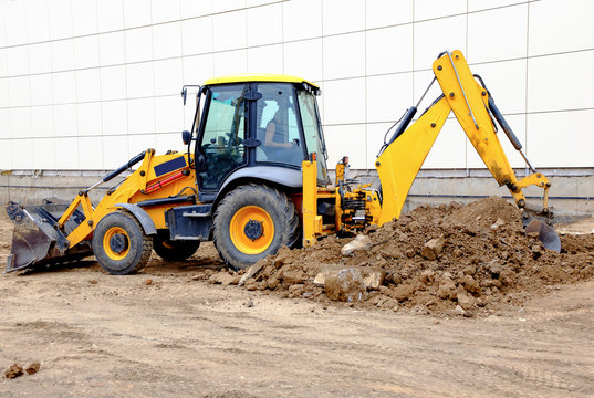 Yellow excavator working with a lot of soil