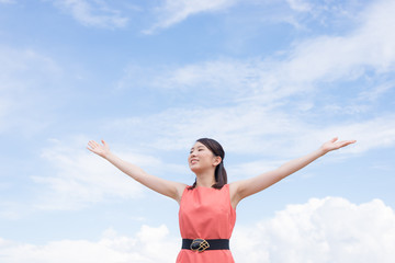 腕を広げる女性と空