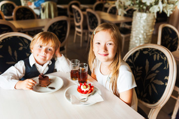 Adorable children eating cakes in a beautiful cafe