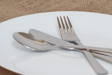 Fork, knife and spoon on white glass plate