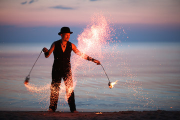 Showman spinning fire poi, sparks of fire
