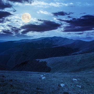 stones on the hillside of mountain range in full moon light