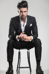 Handsome young man in tuxedo sitting on a stool