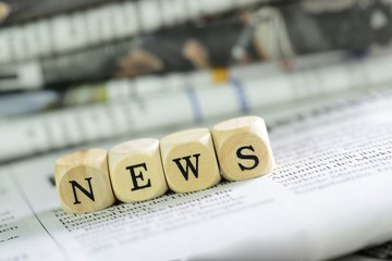 Würfel mit Buchtsaben auf Zeitung