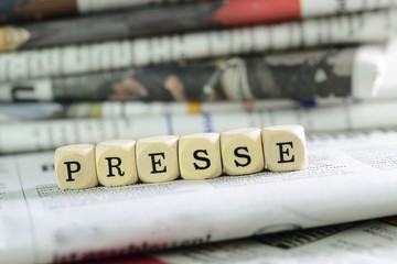 Würfel mit Buchtsaben auf Zeitung