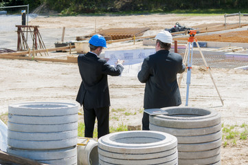 architekten mit bauplan vor baugrube